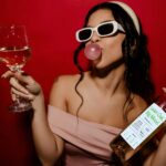 Bennu Chardonnay girl in sunglasses and pink dress with a glass of wine and a wine bottle