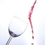 Pinot Noir red wine being poured next to a glass