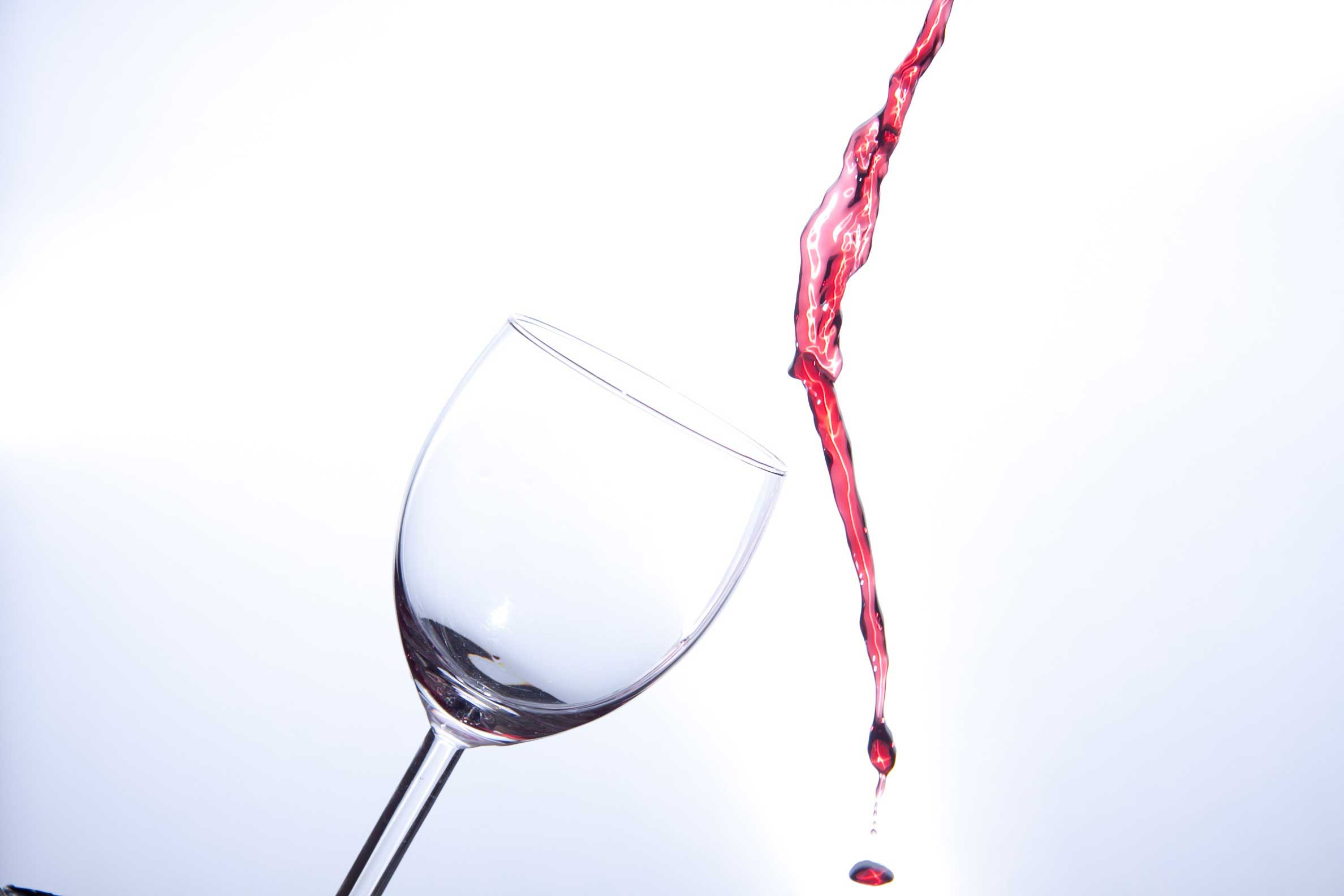 Pinot Noir red wine being poured next to a glass