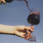 Person pouring Bennu red wine into a glass