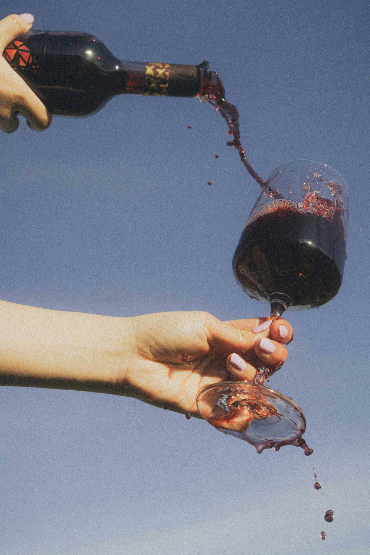 Person pouring Bennu red wine into a glass